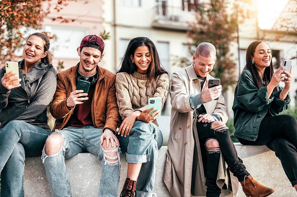 Jugendliche mit Smartphones auf Mauer 