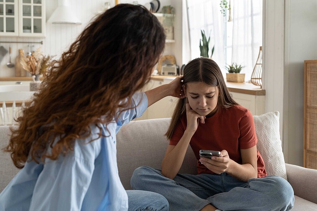 Besorgte Jugendliche am Smartphone wird getröstet