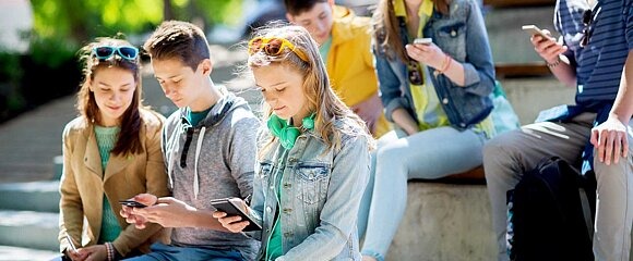 Jugendliche mit Smartphones sitzen auf Treppe