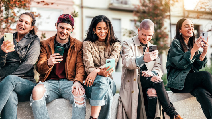 Jugendliche mit Smartphones auf Mauer